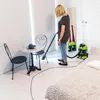 A woman is vacuuming a room with a wet and dry vacuum cleaner. Anteprima dell’immagine prodotto