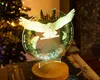 A Harry Potter themed night light with an owl is displayed on a table next to a book and a Christmas tree. Produktbild-Vorschau