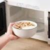 Eine gefüllte Schale wird vor die geöffnete Mikrowelle gehalten. Voir les images du produit