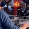 A person wearing headphones is playing a video game on a computer monitor. Produktbild-Vorschau