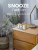 A wooden digital alarm clock is placed on a wooden nightstand next to a plant and a lamp. Produktbild-Vorschau
