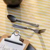A spoon and fork are laid out on a striped tablecloth next to a clipboard with a note. Podgląd zdjęcia produktu