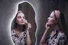A woman applying makeup in front of a decorative mirror with LED lighting. Produktbild-Vorschau