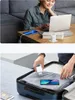 A woman is working on a laptop with a phone charging next to it, and a person is packing a suitcase with a phone and charger. Náhľad obrázku produktu