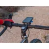A person's hand wearing a red and black glove is holding the handlebars of a bicycle. A smartphone is mounted on the handlebars using a Quad Lock Pro bike mount. Náhled obrázku produktu