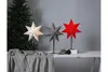 Three star-shaped lamps are displayed on a table next to a Christmas tree. Podgląd zdjęcia produktu