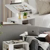 A split image showing a white nightstand with a laptop and magazines in two different settings: one next to a bed and one next to a sofa. Anteprima dell’immagine prodotto