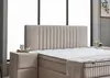 A bedroom scene featuring a boxspring bed with a headboard and a bedside table. Produktbild-Vorschau