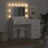 A white vanity table with a lighted mirror and shelves, a stool, and a basket in a room. Voir les images du produit
