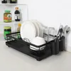 A black dish drying rack on a countertop with dishes, glasses, and cutlery. Produktbild-Vorschau