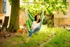 A woman relaxing in a hammock chair in a garden with a cat nearby. Náhled obrázku produktu