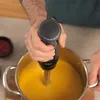 A person is using an immersion blender to blend soup in a pot. Anteprima dell’immagine prodotto