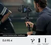 A person is holding a camera stabilizer with a camera attached, seemingly in an outdoor setting. Náhled obrázku produktu