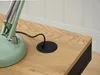 A close-up view of a desk with a green desk lamp and a black cable grommet. Podgląd zdjęcia produktu