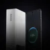 A silver power bank is placed next to a smartphone that is charging. Produktbild-Vorschau