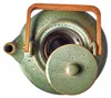 A top-down view of a green ceramic teapot with a wooden handle and a metal tea strainer. Produktbild-Vorschau