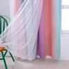 A close-up view of a double-layered curtain with a gradient of pink, purple, and teal colors, adorned with small stars. A sheer white lace-trimmed curtain is layered in front of it. Voir les images du produit