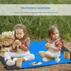 Two young girls are having a picnic on a blue blanket outdoors. Produktbild-Vorschau