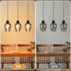 A split image showing a dining table with pendant lights above, one side with lights on and the other with lights off. Produktbild-Vorschau