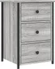 A close-up, front-facing view of a gray wood-effect nightstand with three drawers and black metal accents. Produktbild-Vorschau