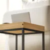 A laptop is placed on a wooden and black side table next to a white sofa. Podgląd zdjęcia produktu