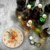 A clock with a cocktail design and several bottles of drinks on a textured surface. Produktbild-Vorschau