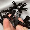 A close-up shot of a pile of black sawtooth picture hangers, held in a person's hand. Produktbild-Vorschau