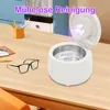 A white ultrasonic cleaner is shown on a wooden desk next to a pair of black-rimmed glasses. Produktbild-Vorschau