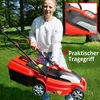 A woman is holding a red electric lawnmower in a grassy yard with trees in the background. Produktbild-Vorschau