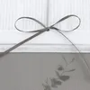A close-up of a grey ribbon tied in a bow on a white background with text printed on it. A sprig of eucalyptus is visible in the lower right corner. Produktbild-Vorschau