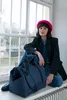 A woman sitting by a window with a duffel bag. Voir les images du produit