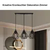 A modern interior scene featuring a three-light pendant lamp with geometric metal shades, a decorative circular wall art piece, and curtains. Produktbild-Vorschau