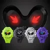 Four G-Shock watches in different colors are displayed in front of a black, stylized graphic resembling eyes with red arrows. Produktbild-Vorschau