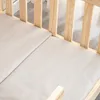 A close-up view of a wooden crib with beige mattresses. Anteprima dell’immagine prodotto