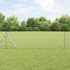 A chain-link fence in a grassy field with trees in the background. Voir les images du produit