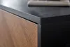 A close-up shot of the corner of a modern TV stand, showing the textured black top and a wooden drawer front with a chevron pattern. Produktbild-Vorschau