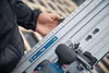 A person is using a circular saw on a wooden surface, possibly a roof. Produktbild-Vorschau