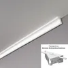 A white decorative molding profile is installed at the junction of a wall and ceiling. A small inset shows a cardboard cutting template with a piece of the molding inserted. Produktbild-Vorschau