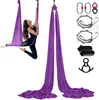 A woman is performing aerial yoga on a purple hammock, with various accessories laid out to the right. Podgląd zdjęcia produktu