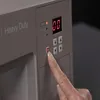 A close-up of a person's finger pressing a button on a sewing machine control panel. Náhled obrázku produktu