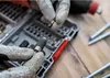 Hands wearing gloves are holding a bit set and a tool bit. Náhled obrázku produktu