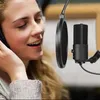 A woman wearing headphones is singing into a microphone with a pop filter in a recording studio. Podgląd zdjęcia produktu