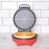 A red and gray waffle maker with a waffle inside, set against a white tiled background. Podgląd zdjęcia produktu