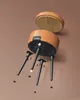 An exploded view diagram showing how to assemble the legs of a round storage stool with a faux leather finish. The stool seat is shown detached from the base. Náhled obrázku produktu