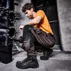 A man is working on machinery while wearing safety boots. Produktbild-Vorschau