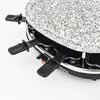 A close-up view of a raclette grill with its granite stone top and black pans. Produktbild-Vorschau