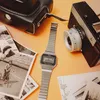 A vintage Casio watch is placed on an orange surface next to old photographs and a vintage camera. Podgląd zdjęcia produktu