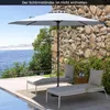 A patio scene with two lounge chairs and a large umbrella next to a body of water and a stone wall. Produktbild-Vorschau
