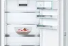 The interior of a white refrigerator with shelves and a bowl of dessert. Produktbild-Vorschau