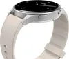 A close-up side view of a silver smartwatch with a white strap against a white background. Produktbild-Vorschau